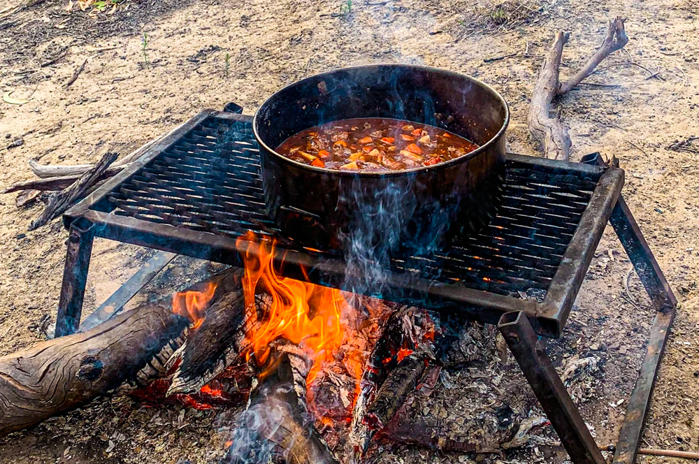 Mitches Camp Oven Beef Casserole simmering over the fire on a cooking grill
